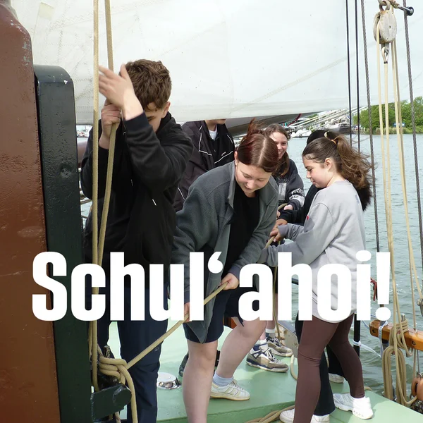Mehrere Jugendliche an Deck eines Segelschiffs, die gemeinsam Taue ziehen und Segel bedienen.